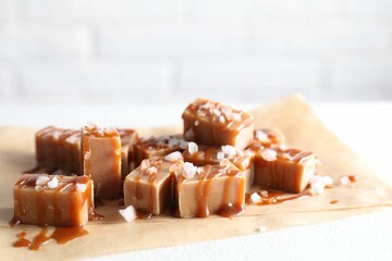 Tasty candies, caramel sauce and salt on white table, closeup