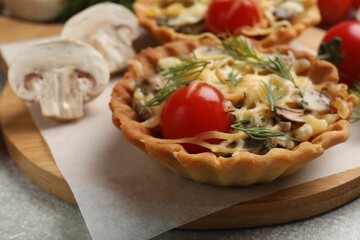 Tasty tartlet with cheese, tomatoes, mushrooms and dill on grey table, closeup