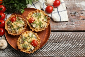 Tasty tartlets with cheese, tomatoes, mushrooms and dill on wooden rustic table, flat lay. Space for text