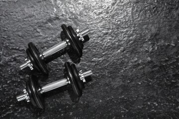 Barbells on dark textured floor, top view. Space for text