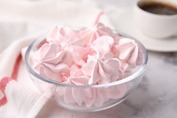 Tasty meringue cookies in bowl on white marble table