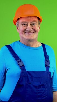 Worker in overalls looking at camera and smiling.