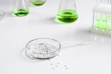 A Petri dish for chemical experiments with white granules against the background of other laboratory glassware.
