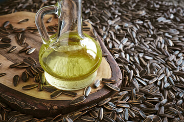 Close-up of many striped sunflower seeds on the table and a bottle with sunflower oil.