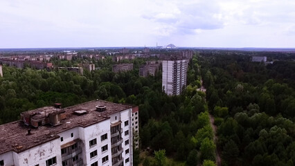 Aerial shot. View of the Chernobyl nuclear power plant through abandoned residential buildings in...