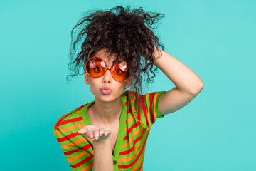 Photo of attractive young woman raise hair sunglass send air kiss dressed stylish striped clothes...