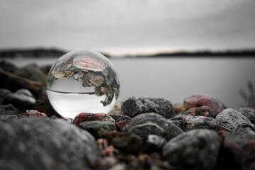Close-up of a crystal ball and stones on beach against sky