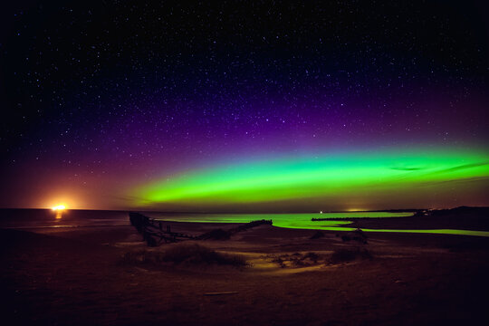 Purple and green Northern Lights over beach and Baltic Sea, Sventoji, Palanga, Lithuania