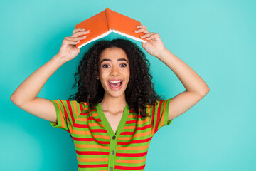 Photo portrait of attractive young woman hold book roof dressed stylish striped clothes isolated on aquamarine color background