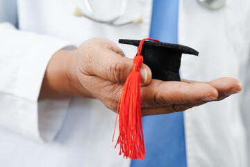  Asian doctor holding graduation gap hat, education medicine.