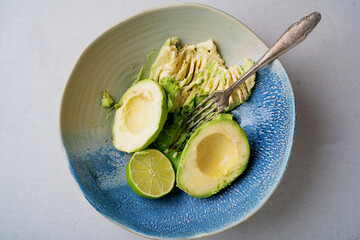 Halved Avocados  with avocado mash in a bowl