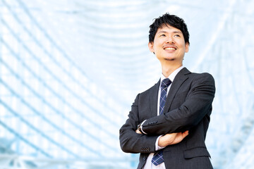 腕組みをして遠くを見つめる笑顔の男性ビジネスマン