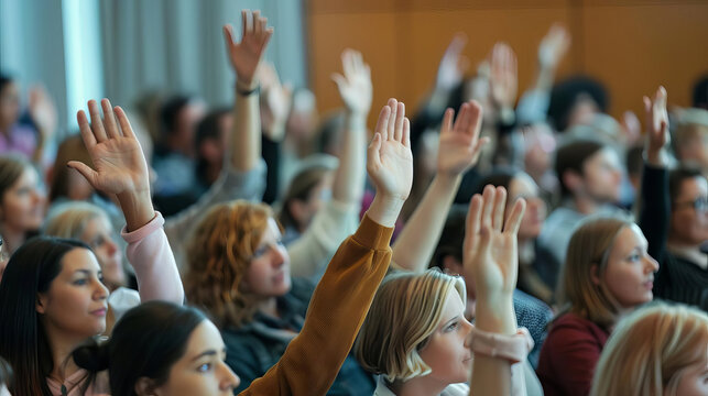 Active, diverse audience raising hands to ask questions during an engaging talk or master class