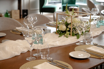 Elegant dining table set for a special event, featuring a beautiful floral centerpiece, wine...