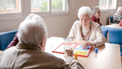 Senior woman playing ludo with friends at table in nursing home