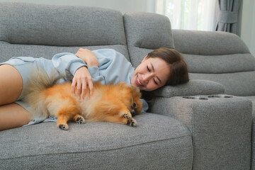 A woman plays and naps with her beloved dog on her favorite sofa in the home.
