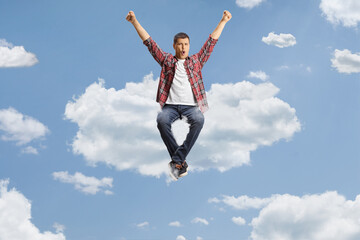 Excited young man sitting on a white cloud and shouting