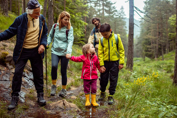 Multi-generational family crossing a stream during a forest hike