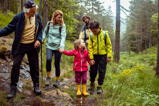 Multi-generational family crossing a stream during a forest hike