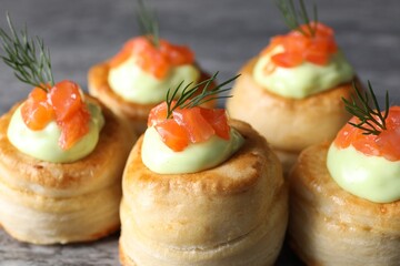 Delicious puff pastry with avocado cream, salmon and dill on table, closeup