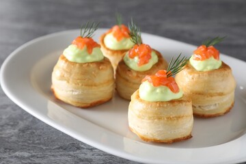 Delicious puff pastry with avocado cream, salmon and dill on grey table