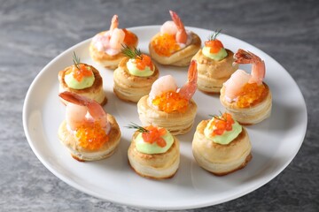 Different delicious puff pastry snacks on grey table