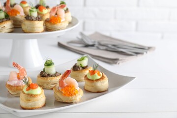 Different delicious puff pastry snacks on white wooden table