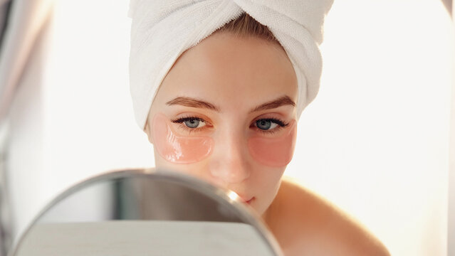 Anti-age cosmetic. Moisturizing patches. Refreshing morning care. Young woman achieving fresh look applying hydrogel under eye product.