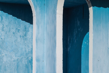 Blue and white grungy concrete arch, old exterior details, abstract photo