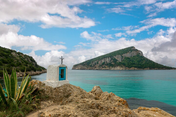 Religious Christian cross on a rock by the mediterranean sea, coastal landscape, Capo Figari near...