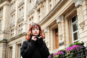 Intense portrait of young woman in front of old building.