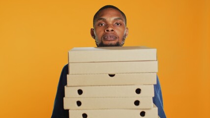 Clumsy deliveryman dropping a huge stack of pizza boxes in studio, wasting a lot of food and making...