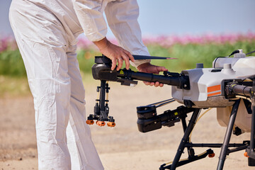 A male in a white uniform preparing an agrodrone for flying over a field.