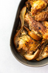 Baked chicken with pears and thyme, oval dish with baked chicken parts