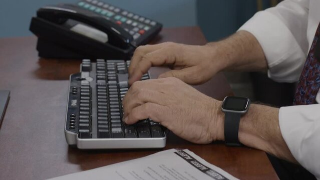 Elderly police officer on computer doing paperwork in precinct