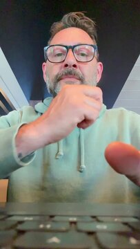 Laptop camera view pov of adult man at work on computer writing and typing on keyboard with concentrated expression. People online work. Workplace and modern businessman. Emails notification message