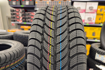 Winter tire for a car in a store. Winter season. Choosing winter tires for a car. Road safety.