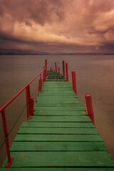 Naklejka premium Old wooden walkway used as a pier painted in striking colors, green and red, in Puntal de Somo, Santander