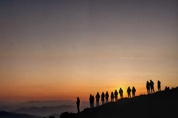 silhouette of several friends watching the sunset over the landscape