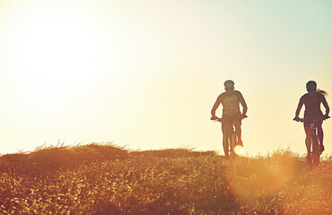 Fototapeta premium Sunset sky, people and team in bicycle race with grass, exercise and adventure trail in nature together. Cycling, fitness and friends with mountain bike in evening for outdoor workout, sun and mockup