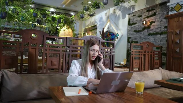 Experienced general manager giving instructions to assistants online while having lunch in a luxury hotel restaurant. Women in business concept