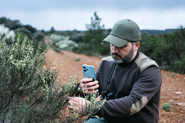 Ecologist park ranger working on the National park Reserve monitoring plant health with mobile app