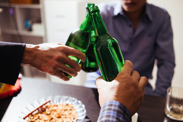 A group of businessmen hold beer bottles and clink each other as a sign of celebrating the success...