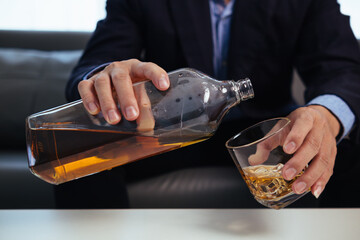 businessman sits alone in his office drinking brandy after discussing and agreeing with investors to do business in meeting until reaching satisfactory conclusion. concept of relaxing with brandy