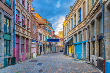 Empty narrow cobblestone street, paving stone road, old colorful buildings with brick walls in...