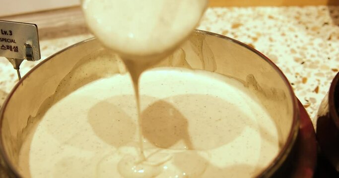 Spoon scoops cheese sauce in a white cup close up sheese souce. Scoop mayonnaise