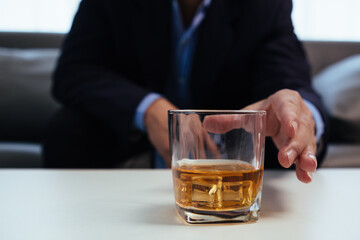 businessman sits and holds glass of liquor in his hand to drink relieve stress after experiencing...