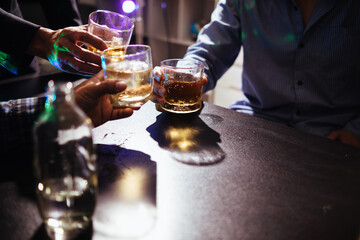 A group of businessmen held brandy glasses together to cheers glasses of brandy after concluding negotiations on business ventures and reaching a satisfactory agreement for joint business profits.