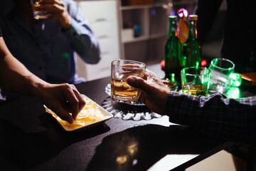 A group of businessmen held brandy glasses together to cheers glasses of brandy after concluding negotiations on business ventures and reaching a satisfactory agreement for joint business profits.