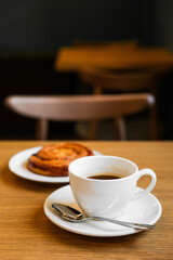 Pain aux raisins, bun with raisins and a cup of coffee on wooden table